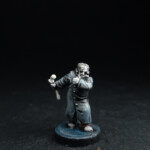 Une figurine du 7ème, Dr. Frankenstein, vue de face, enroulé dans un manteau gris noir et tient une massue d’os dans la main.