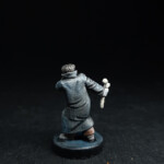 Une figurine du 7ème, Dr. Frankenstein, vue de derrière, enroulé dans un manteau gris noir et tient une massue d’os dans la main.