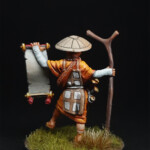 Noshin Une figurine de Okko Chronicles, Noshin de derrière, avec son bâton et qui montre un parchemin.