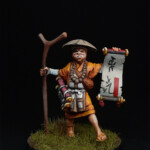 Noshin Une figurine de Okko Chronicles, Noshin de face, avec son bâton et qui montre un parchemin.