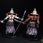 Hanyo-Shiro et Hanyo-Aka Duo de figurines d’Okko Chronicles, Hanyo-Shiro et Hanyo-Aka, personnage démonique vue de derrière, l’un de couleur blanche, l’autre rouge, le visage caché par un chapeau de paille et chacun équipé de deux armes.