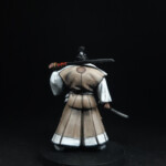 Hiroji san Une figurine d’Okko Chronicles, Hiroji san, personnage vue de derrière, d’une stature imposante, habillé d’un kimono beige, équipé d’une épée, son fourreau dans l’autre.