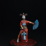 Isako Une figurine de Okko Chronicles, Isako, jeune femme marionnettiste de face, vêtue d’une robe rouge, un éventail dans la main et une marionnette dans l’autre.