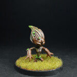 Kami de terre Une figurine de Okko Chronicles, Kami de terre, petite créature faite de bois avec des cheveux parsemés de feuilles.