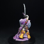 Marionnettiste Une figurine d’Okko Chronicles, Marionnettiste, personnage de derrière, habillé d’un kimono violet équipé d’une épée et de marionnettes.