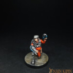 Le Mécano Une figurine de Nemesis, le mécano, personnage accroupi, vêtu de vêtement orange.