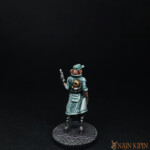 La Medic Une figurine de Nemesis, la medic, personnage féminin vue de derrière, vêtu de vêtement bleu, son arme dans la main.
