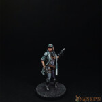 La Medic Une figurine de Nemesis, la medic, personnage féminin vue de face, vêtu de vêtement bleu, son arme dans la main.