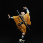 Oni-Sorio Une figurine d’Okko Chronicles, Oni-Sorio, personnage démoniaque vue de derrière, vêtue d’un kimono orangé avec un sourire maléfique.