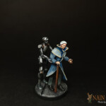 Une figurine de Nemesis, Le PDG, vieux personnage masculin vêtu d’un manteau bleu et accompagné d’un robot humanoïde.