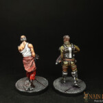 Duo de figurines de Nemesis, Le Chasseur de primes et le Prisonnier, personnage vue de face, barbu et armé pour l’un, vêtu d’un débardeur blanc et qui porte une muselière pour l’autre.