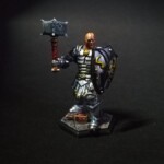 Front view of a D&D character Grand guerrier au crâne chauve habillé d'une armure argenté, i lest équipé d'un marteau dans sa main droite et d'un grand bouclier dans l'autre.
